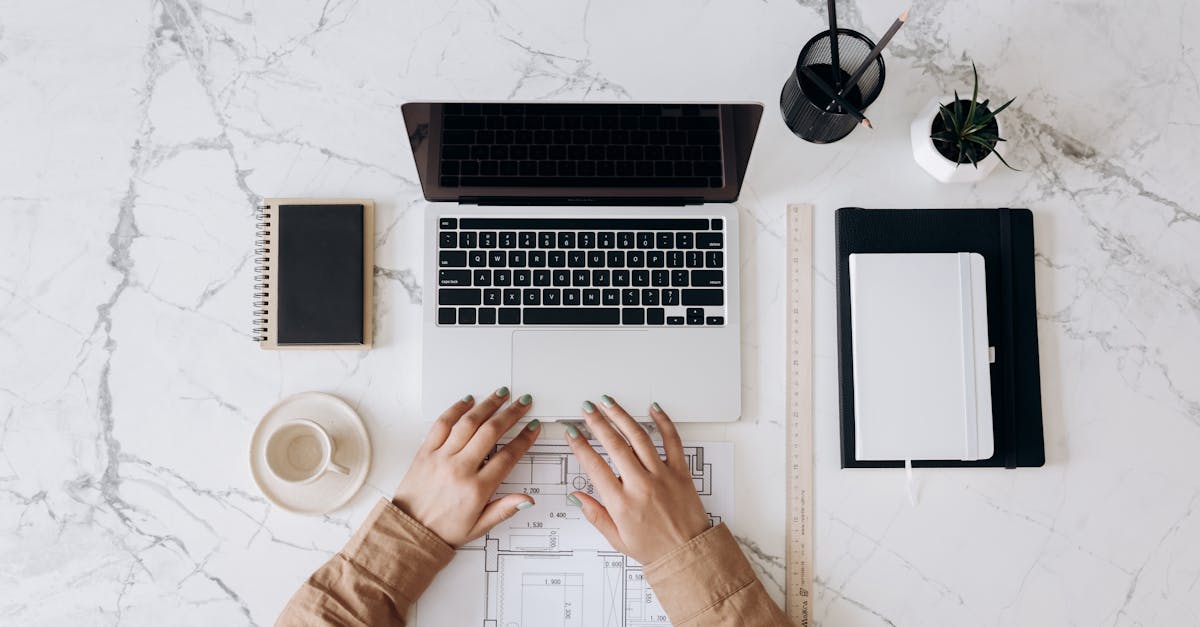 top view of a stylish home office desk with a laptop planner and coffee cup showing hands on a bl
